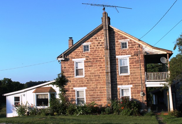 Brick farmhouse with log cabin on left